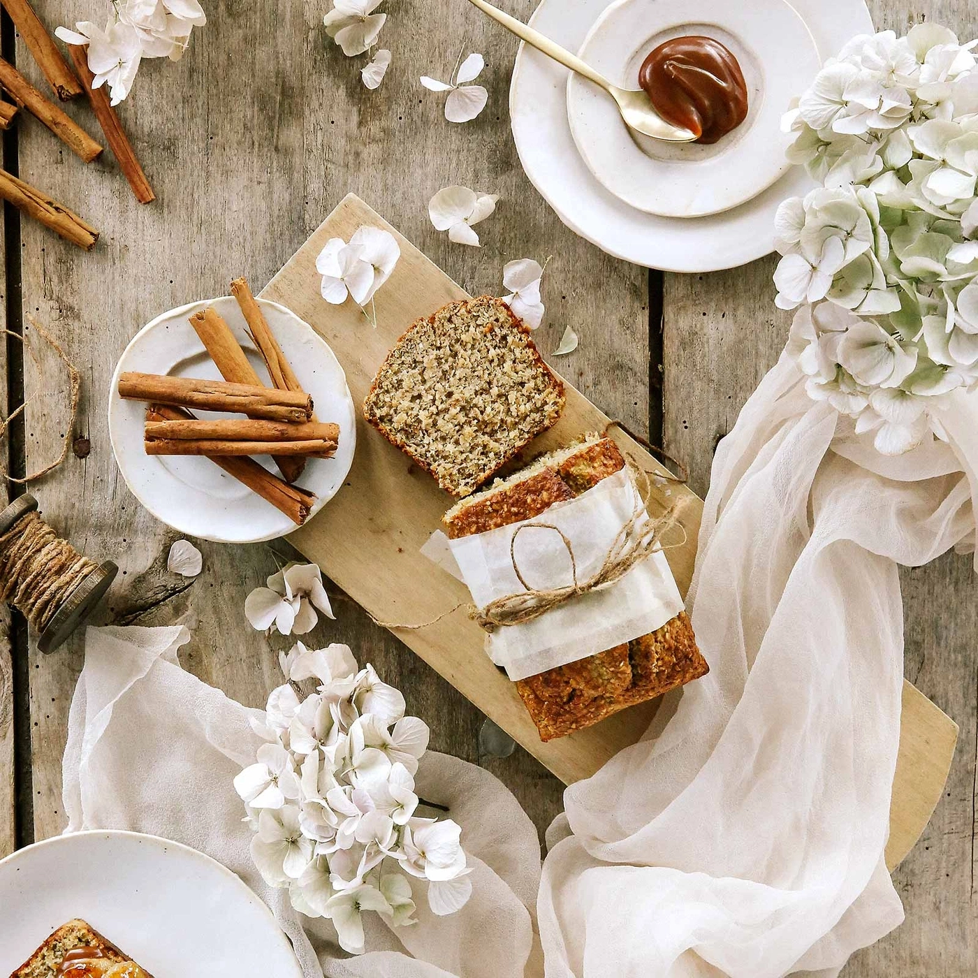 Brot, Zimtstangen, Blumen und Soße auf einem Holztisch. Stillleben.
