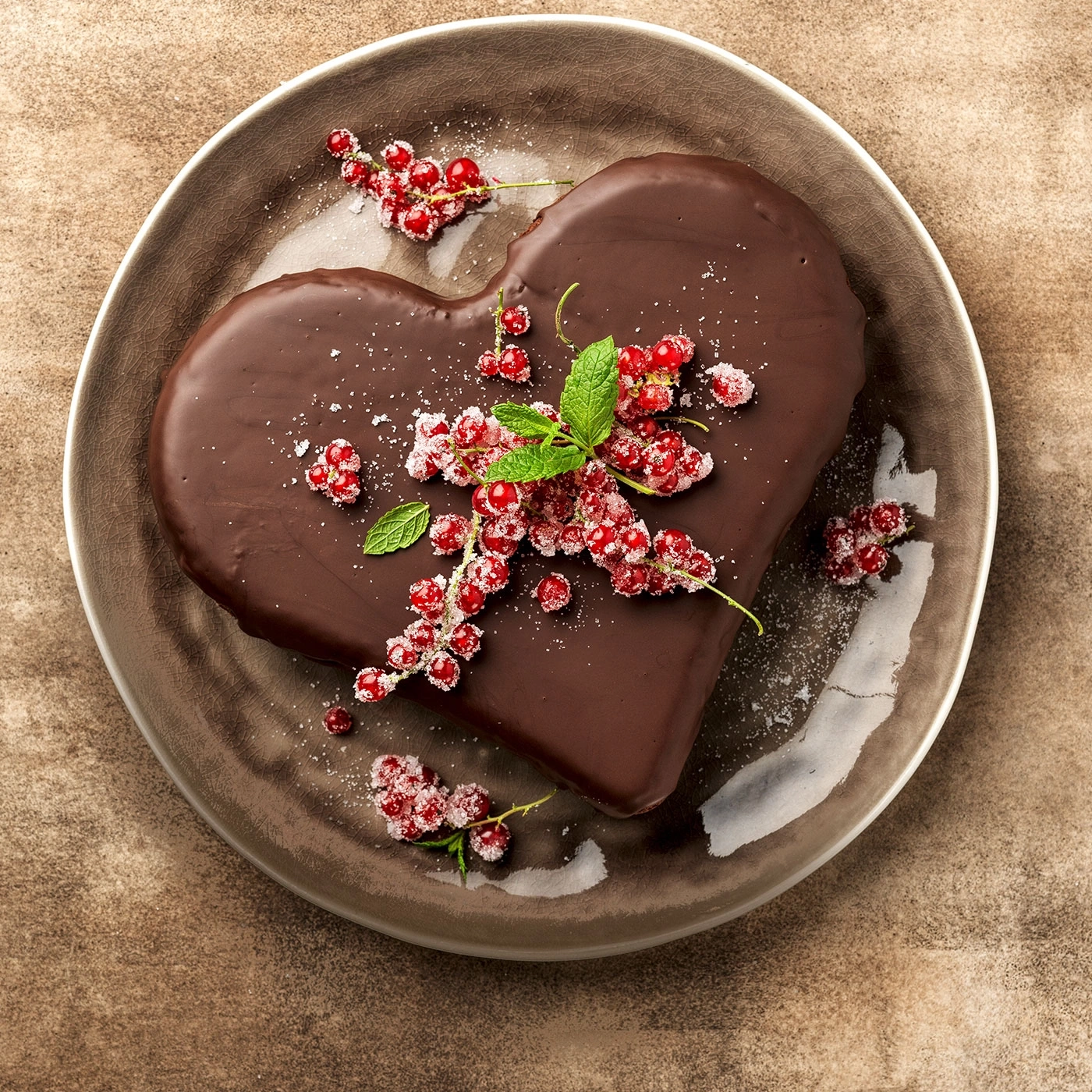 Herzförmiger Schokoladenkuchen mit roten Johannisbeeren auf einem Teller