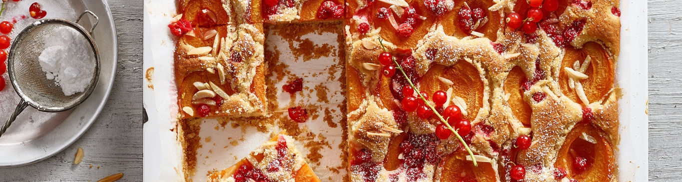Kuchen mit Früchten, Mandeln und Puderzucker, auf einem Backblech