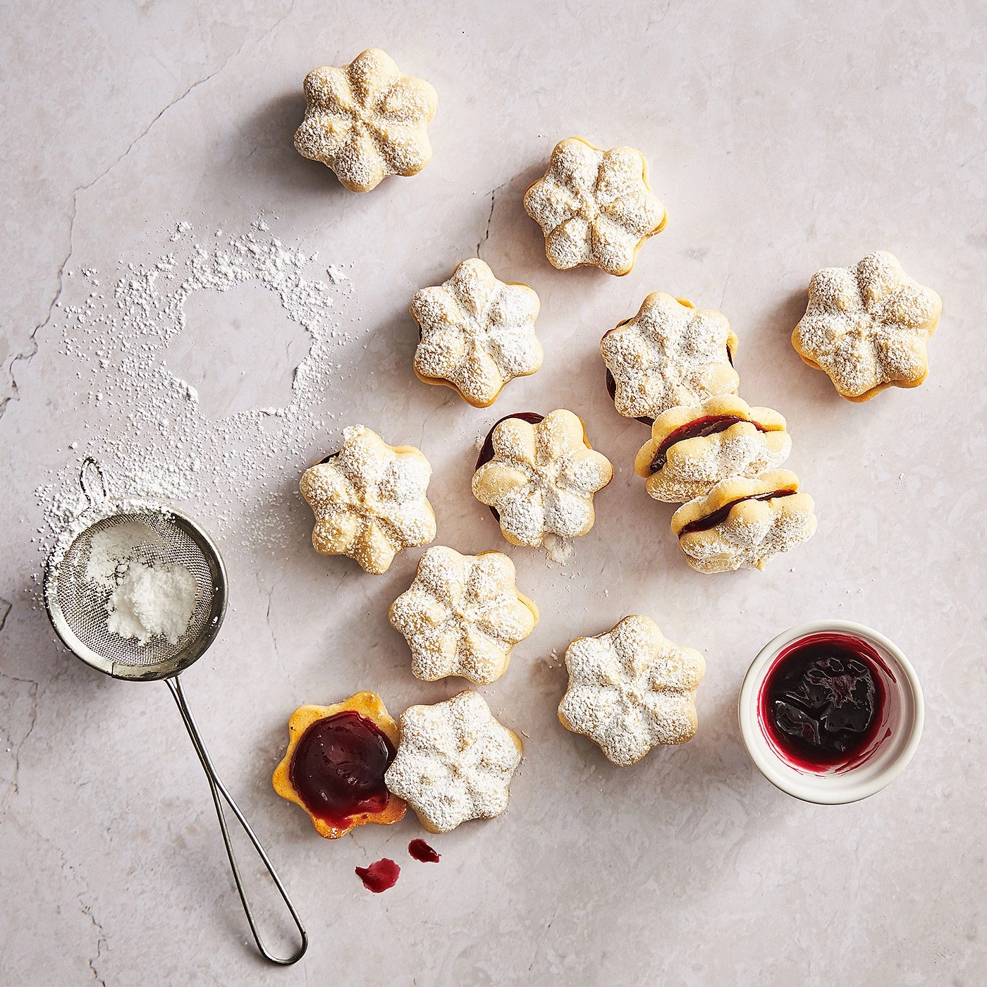 Biscuits saupoudrés de sucre glace et confiture, sur fond clair, gros plan.