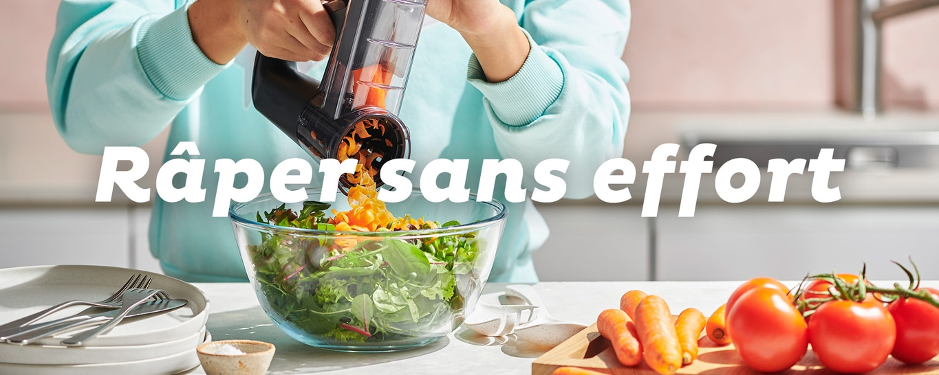 Une personne râpe des carottes dans un bol de salade.