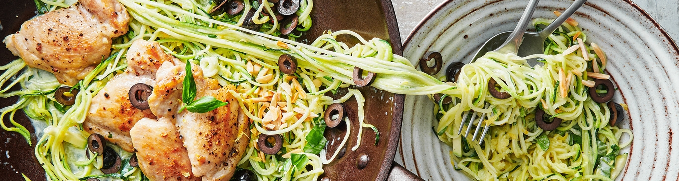 Poulet avec nouilles de courgettes, olives et amandes sur deux assiettes