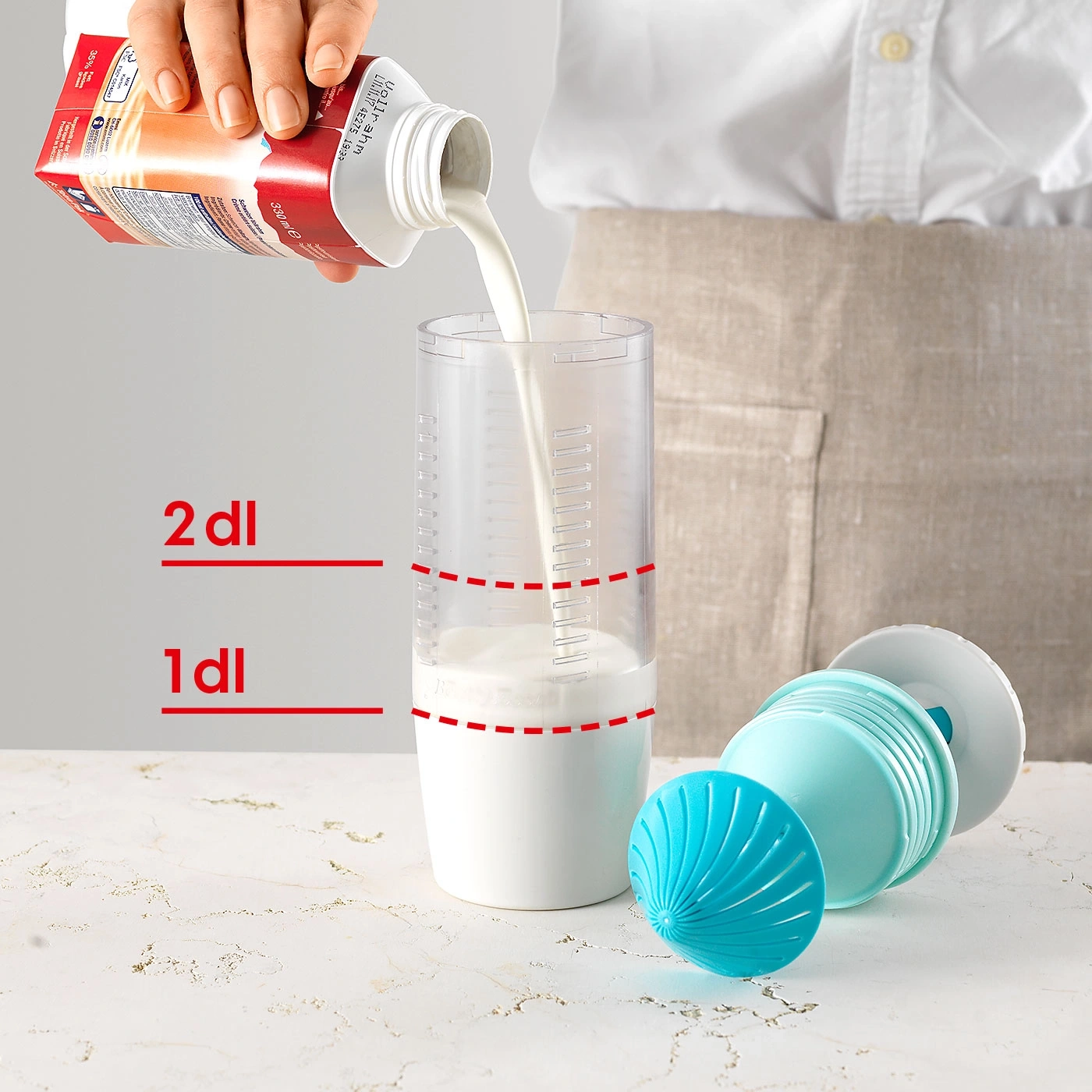 Milch wird in einen Messbecher gegossen, daneben ein Schneebesen.