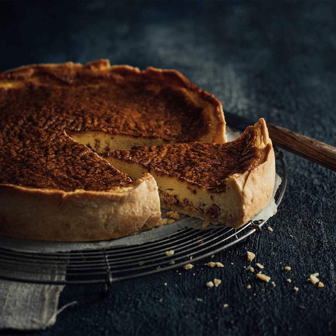 Kuchen mit einer Scheibe, die auf einem Rost liegt, Nahaufnahme, dunkler Hintergrund.