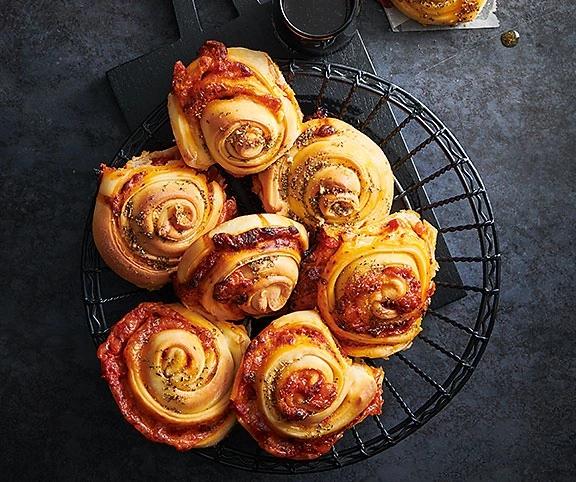 Pizza-Schnecken in einem schwarzen Korb auf dunklem Hintergrund, Nahaufnahme
