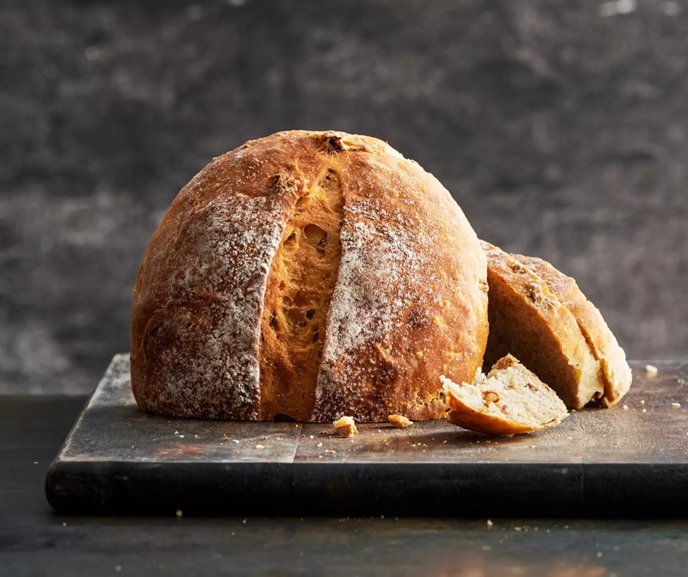 Une miche de pain avec des tranches coupées sur une planche en bois.