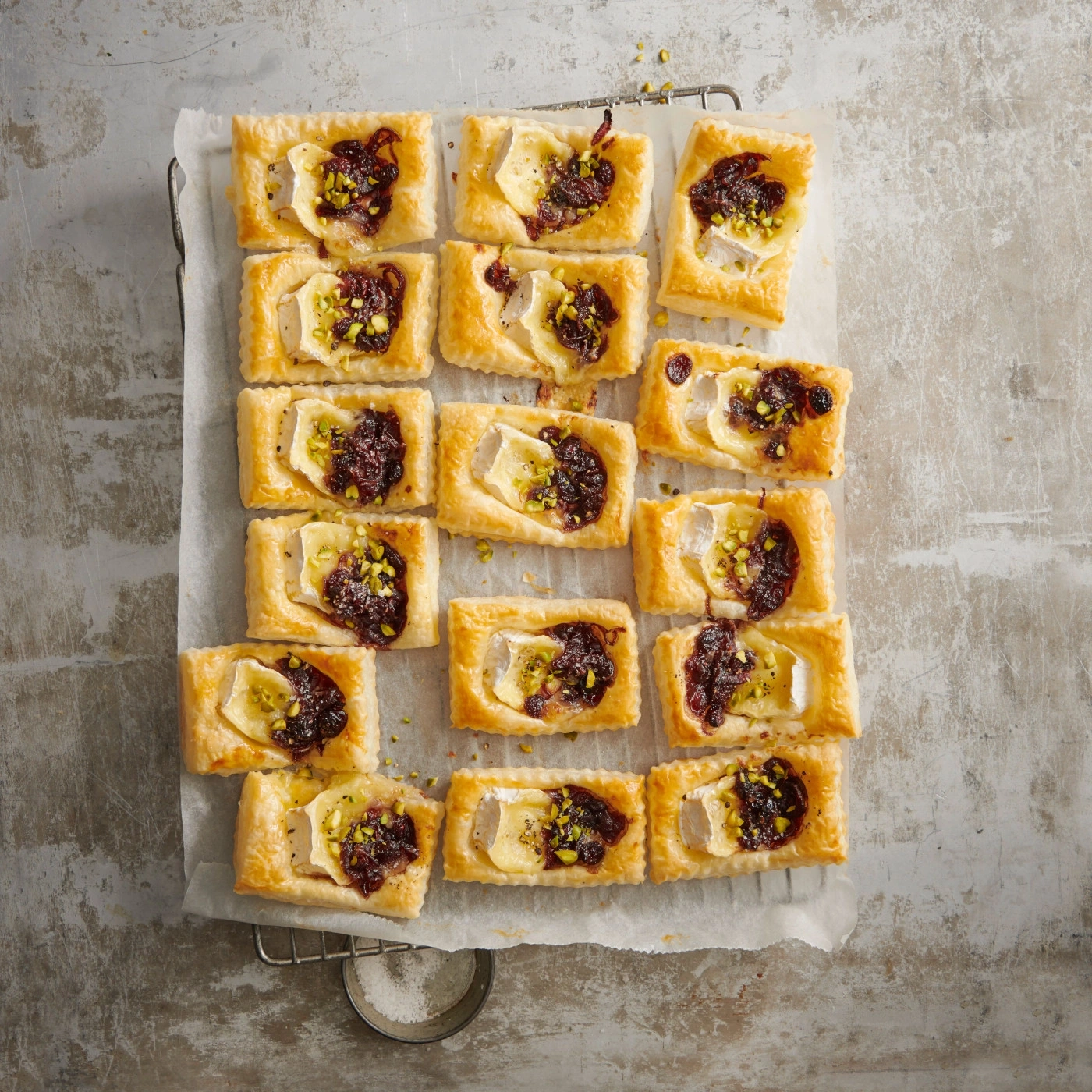 Köstliche Blätterteig-Tartelettes mit Käse, Marmelade und Pistazien auf einem Rost.