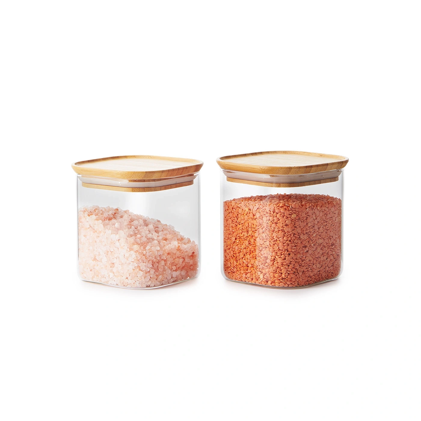 Deux bocaux en verre avec couvercles, remplis de sel et de lentilles, sur fond blanc.