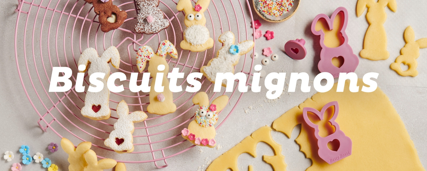 Biscuits de Pâques en forme de lapin sur une grille, avec des emporte-pièces et des vermicelles.