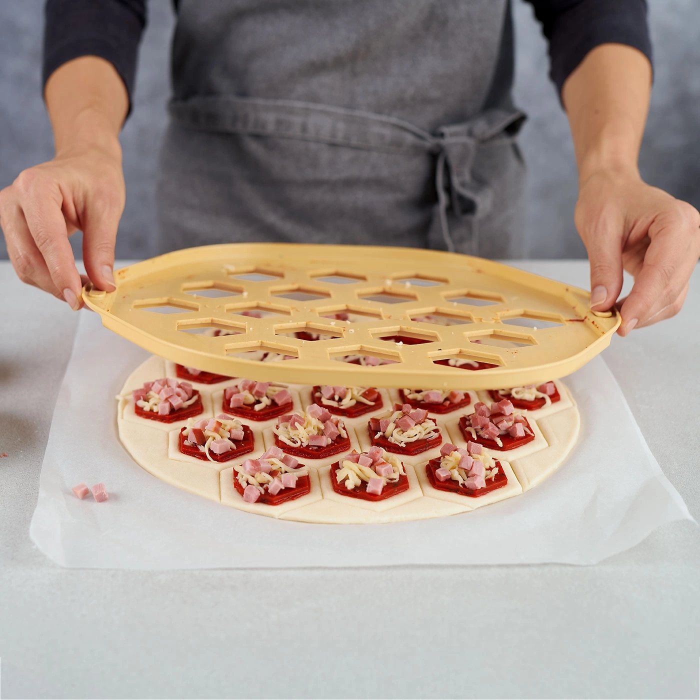 Une personne coupe une pizza en petits morceaux avec un outil spécial.