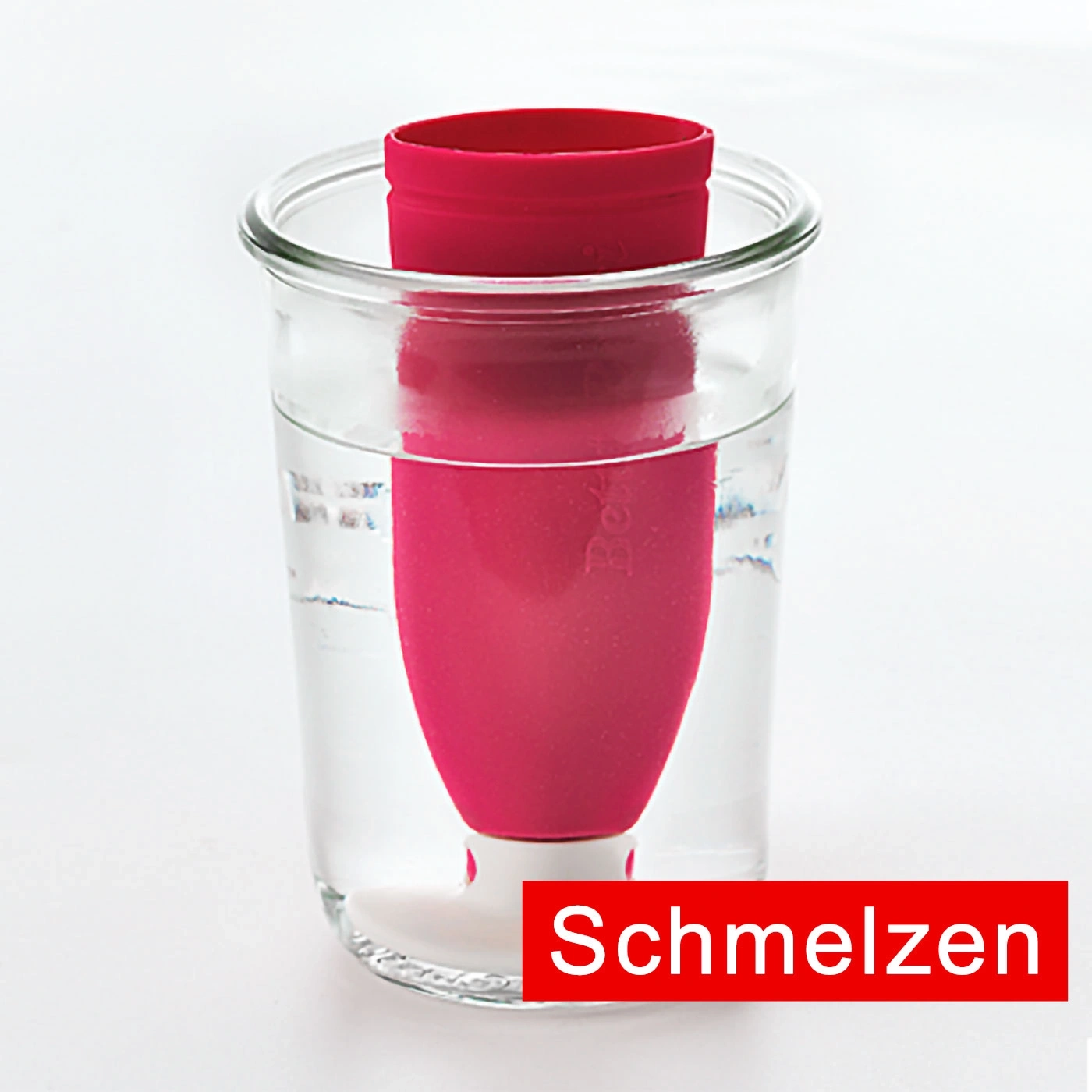 Objet rouge dans un verre d'eau, texte 'Schmelzen' en bas.