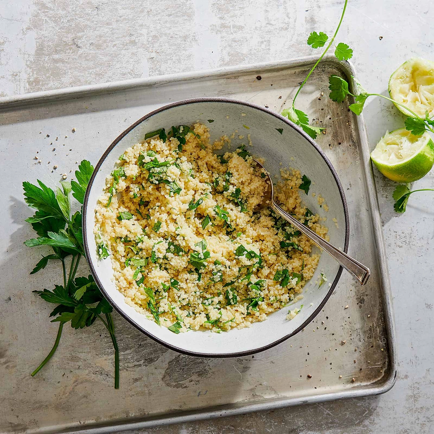 Couscous-Salat mit Kräutern und Limette auf einem Tablett mit Löffel